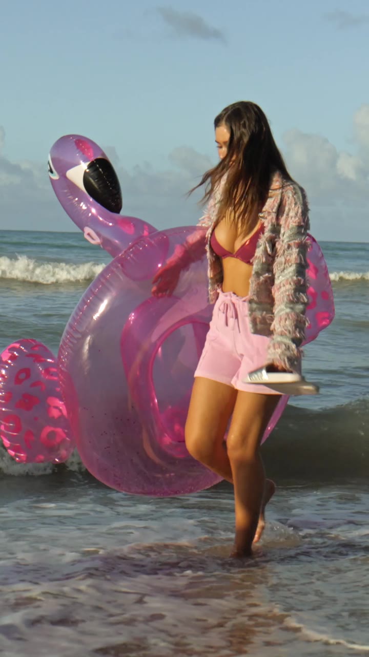 Model am Strand mit pinkem Schwimmring
