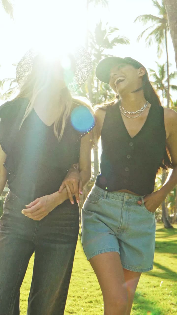 Zwei Models im Sonnenlicht unter Palmen